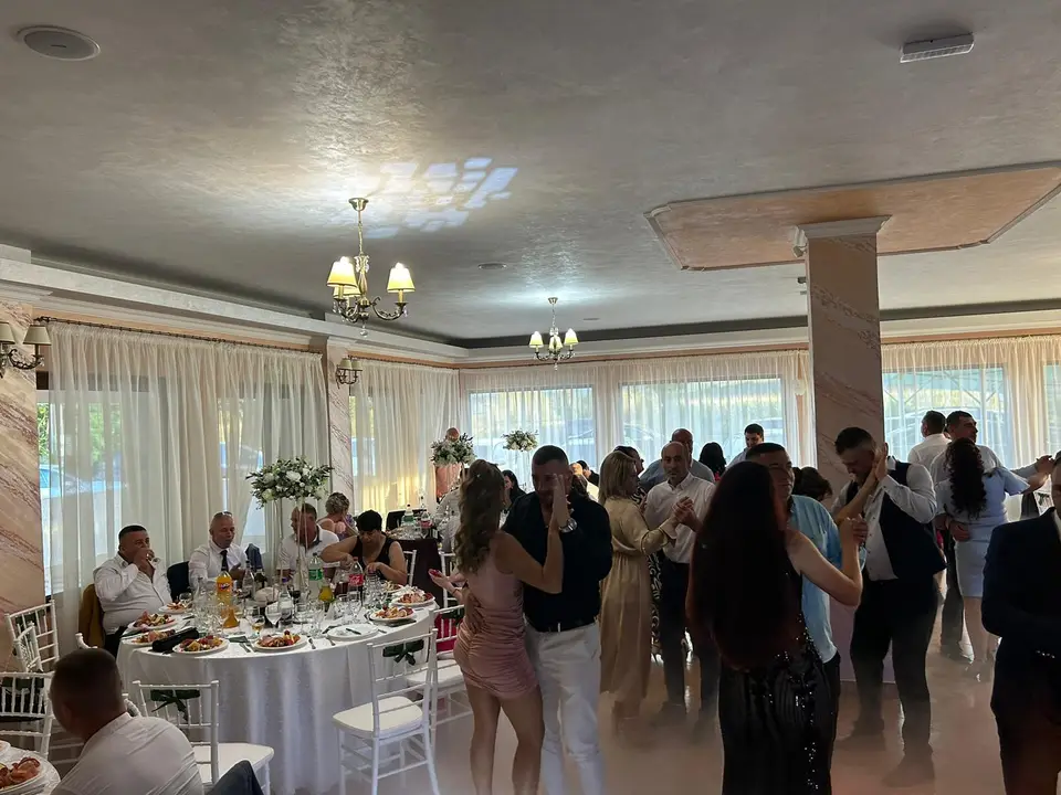 Invitații dansează între mese, la un eveniment